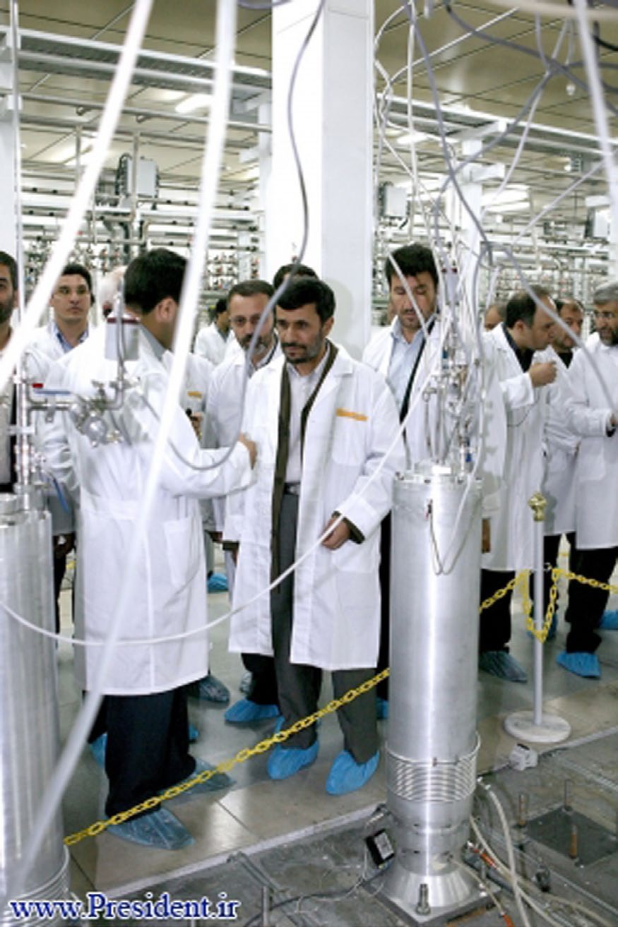 شکل ۸.۱۳. بالا: تصویری از ویدئوی آرشیوی ایران از پایه‌های مجزای سانتریفیوژ در یک تأسیسات ناشناخته. به‌نظر نمی‌رسد این پایه‌ها روتور سانتریفیوژ داشته باشند. پایین: عکسی از وب‌سایت رئیس‌جمهور ایران از یک سانتریفیوژ احتمالی نوع IR-2 که به‌نظر می‌رسد از سانتریفیوژهای تصویر بالا پهن‌تر باشد، با مقایسه عرض آن با افراد نزدیکش.